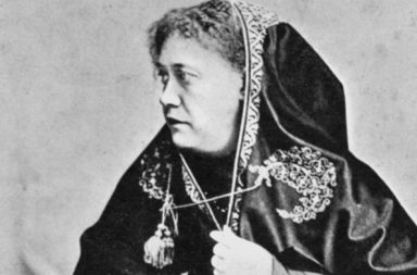 Historical profile photograph of H.P. Blavatsky with an embroidered dark head covering.